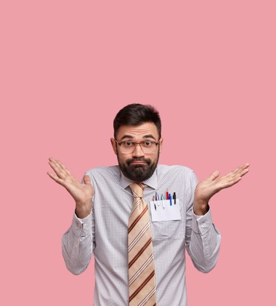 Vertical shot of clueless doubtful Caucasian man with thick stubble has uncertain look, wears formal shirt and tie, tries to make decision, poses over pink background with blank space for information