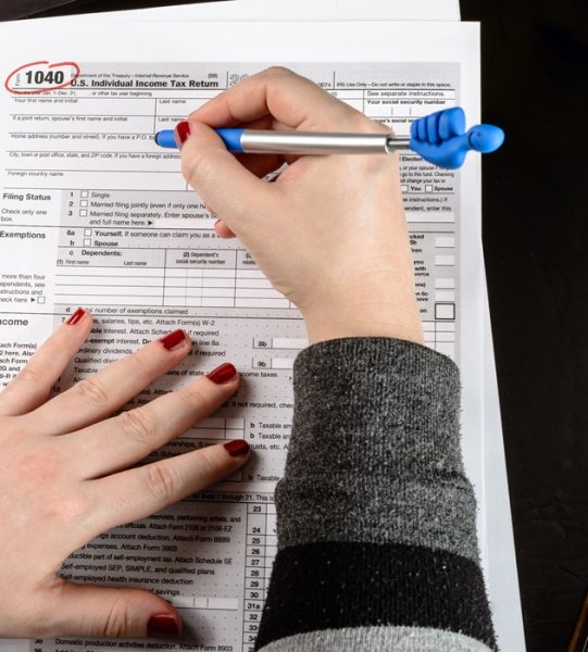 Woman fills the tax form, working with tax documents. Form 1040 Individual Income Tax return form. United States Tax forms. American blank tax forms. Tax time.